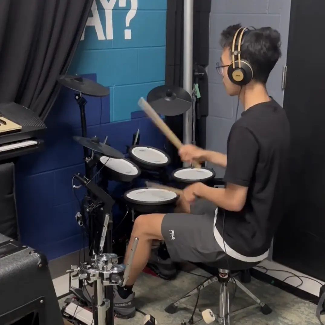 Teenager playing electronic drum kit with headphones
