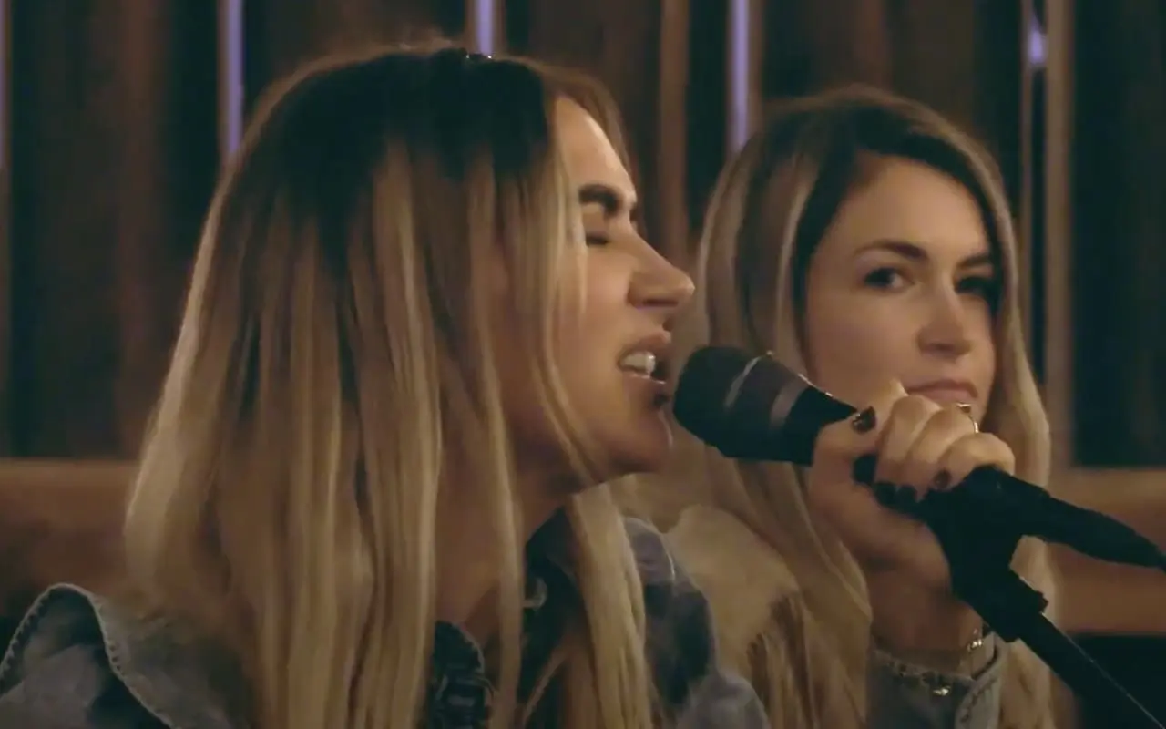 Two women singing into microphones during a performance.