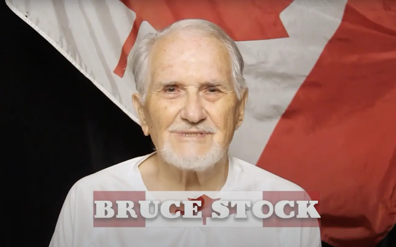 Bruce Stock, veteran, smiling in front of Canadian flag