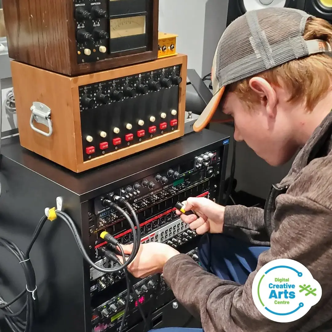 Student connecting audio cables during a creative industry co-op placement.