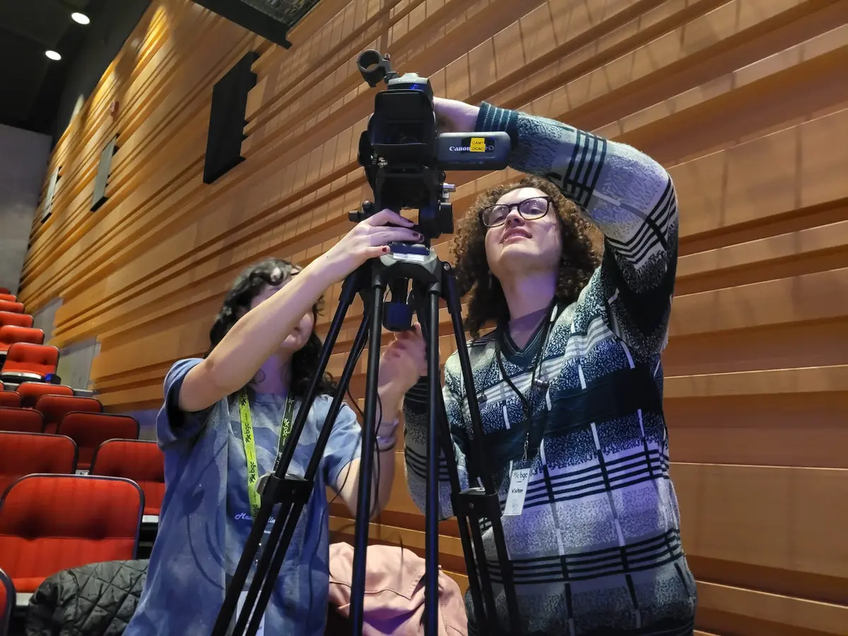 Two students adjusting a video camera on a tripod during a co-op placement in the creative industry.