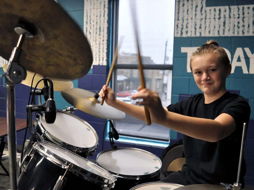 Young boy playing drums during a creative industry co-op placement.